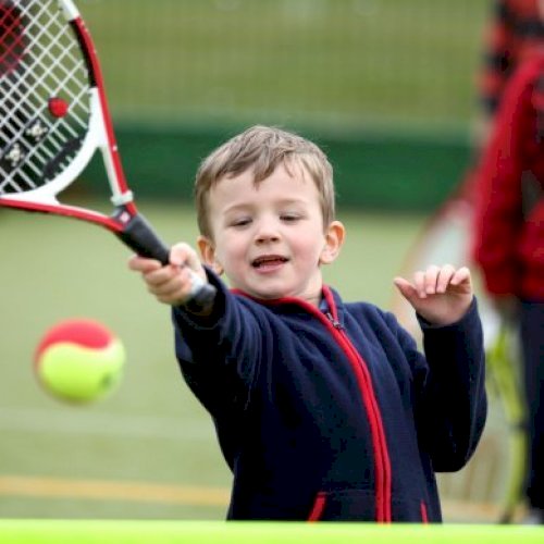 Young child hitting tennis ball